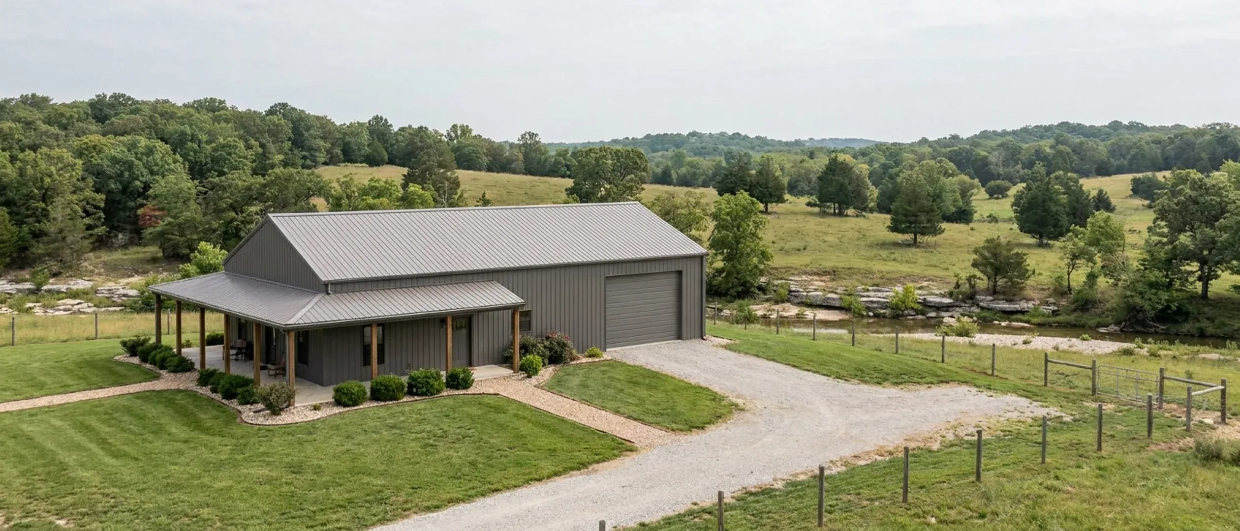 A completed barndominium with a covered entry porch and an attached shop bay, photographed in flat overcast daylight.